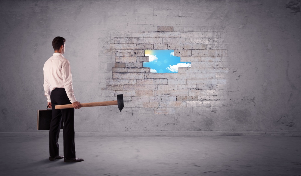 Business man hitting grungy brick wall with hammer