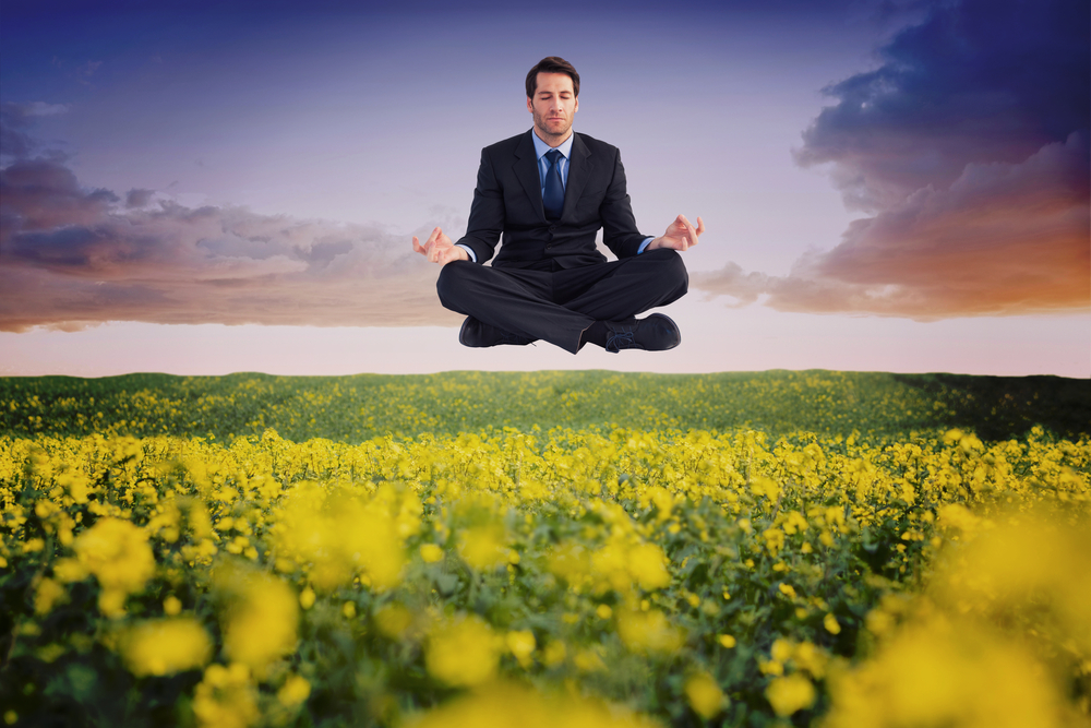 Calm businessman sitting in lotus pose against nature scene