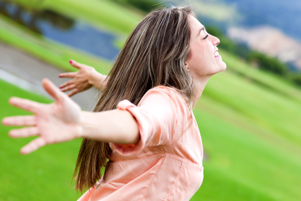 Happy woman relaxing outdoors with arms open