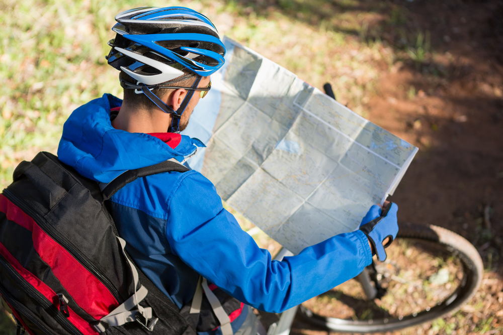 Male mountain biker looking at map in the forest