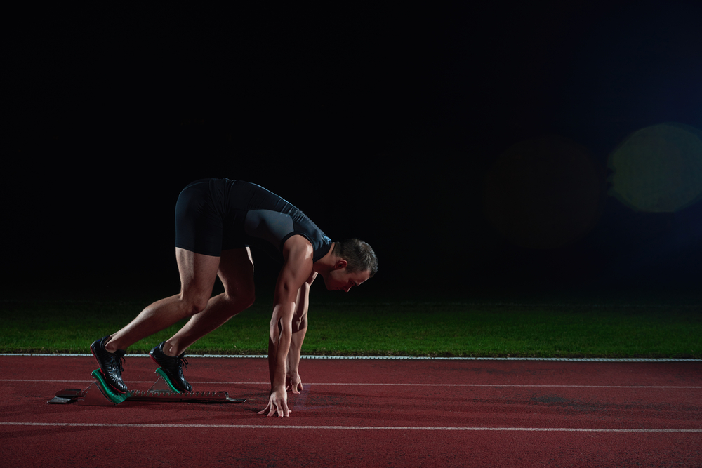 Sprinter leaving starting blocks on the running track. Explosive start.