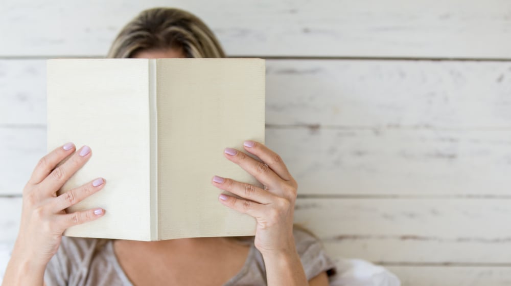 Woman reading a book and covering her face